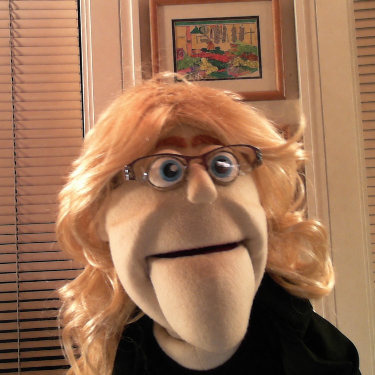 Leena, a red-haired puppet with glasses, looks toward the camera