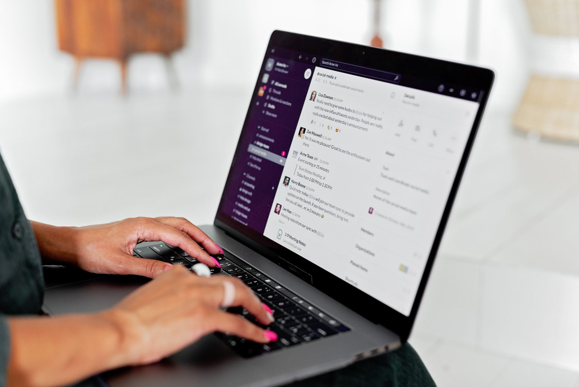 person typing on laptop with coloured fingernails